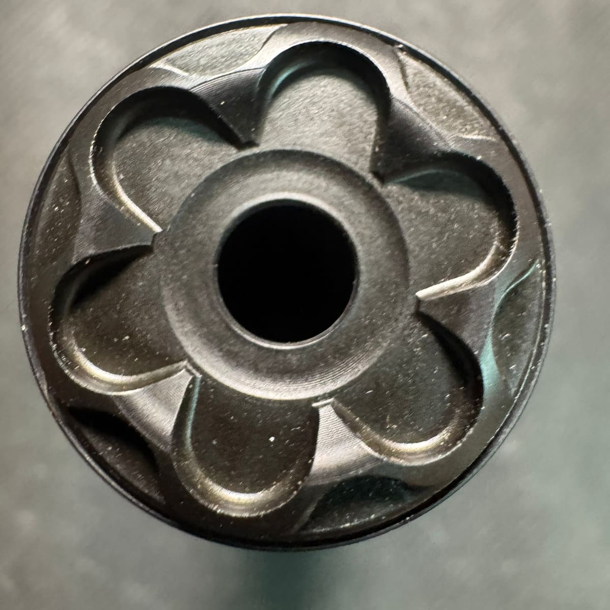 Close-up looking directly into the muzzle end of the Rugged Oculus22, showing the bore surrounded by a symmetrical petal-shaped baffle geometry machined into the stainless end cap.