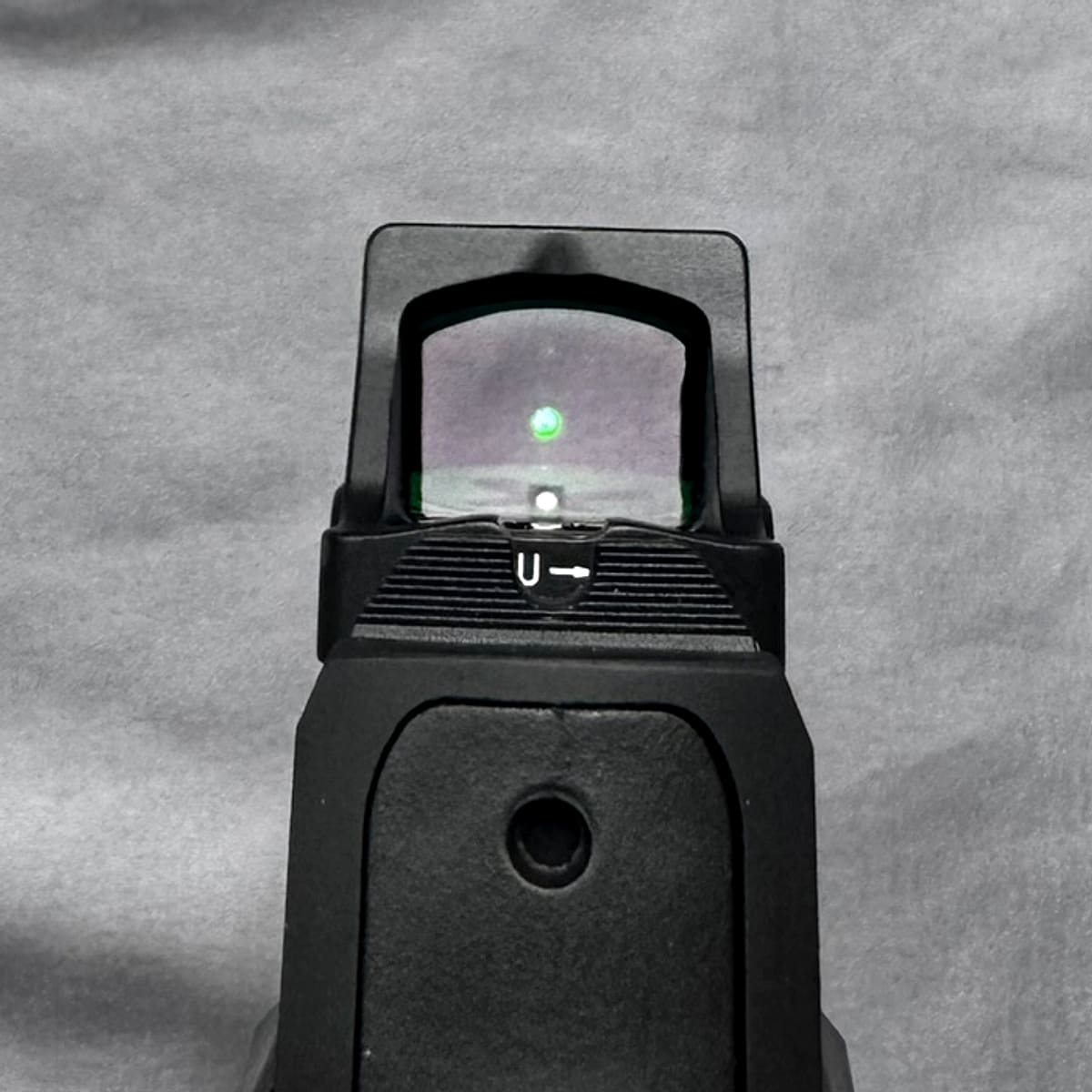 Looking through the Vortex Defender-CCW window at a green aiming dot, photographed from behind the pistol.