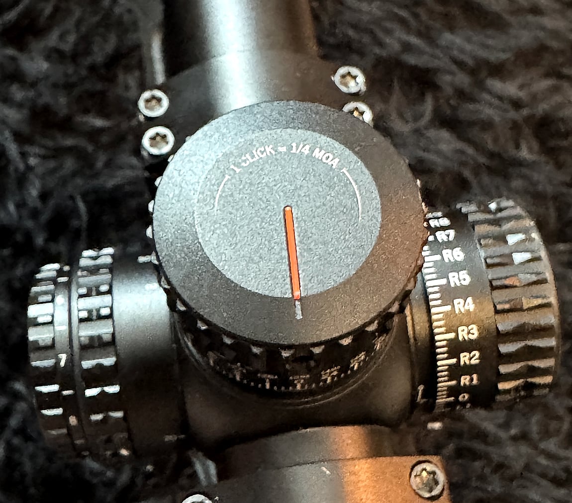 Top-down view of the Viper PST elevation turret, the cap engraved 1 CLICK = 1/4 MOA with an orange index line, surrounded by several hex screws, with the windage turret and its R1 through R8 graduations alongside.